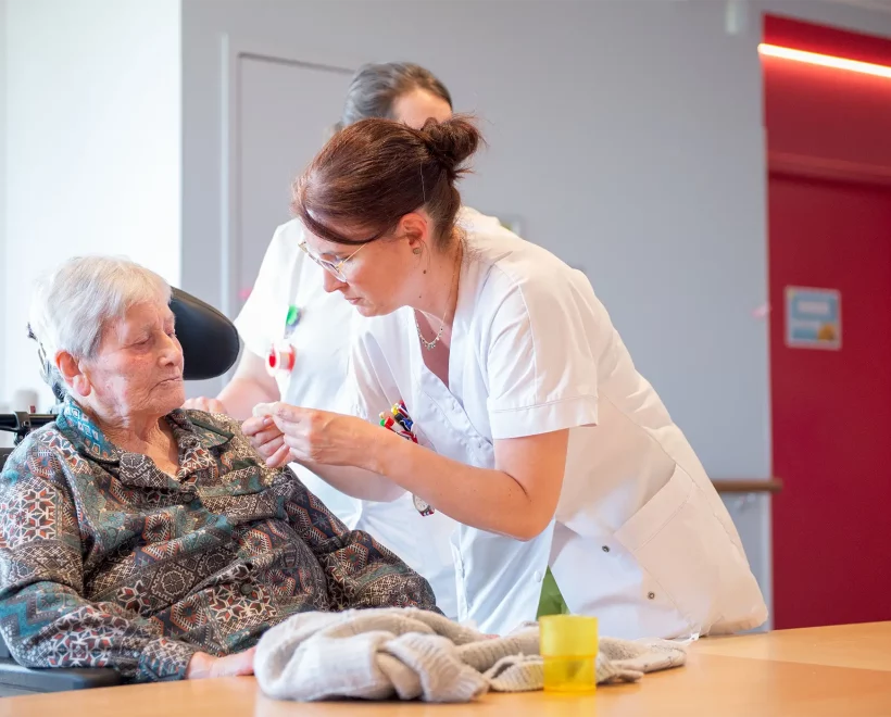 soignante qui s'occupe d'une résidente en fauteuil
