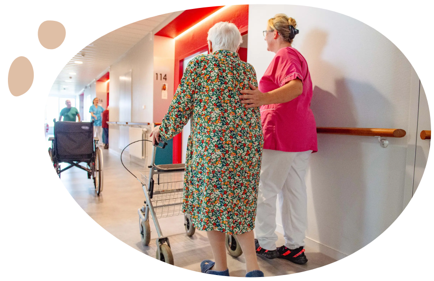 résidente marchant dans le couloir avec un déambulateur avec sa soignante